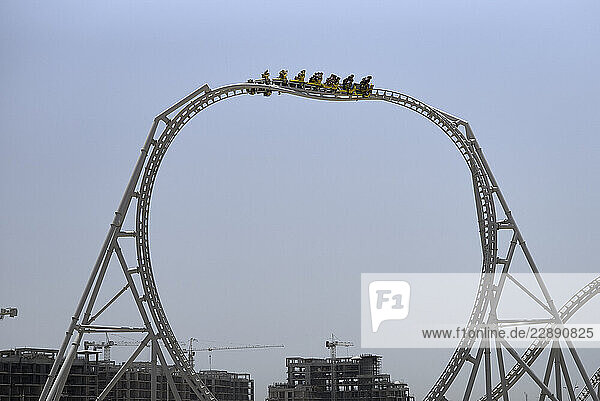 A roller coaster reaches the peak of a loop against a clear blue sky. Abu Dhabi  UAE