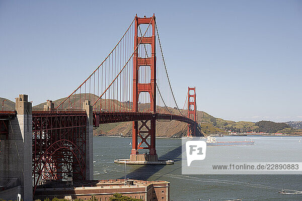 Golden Gate Bridge with clear sky and a cargo ship passing underneath. San Francisco  USA