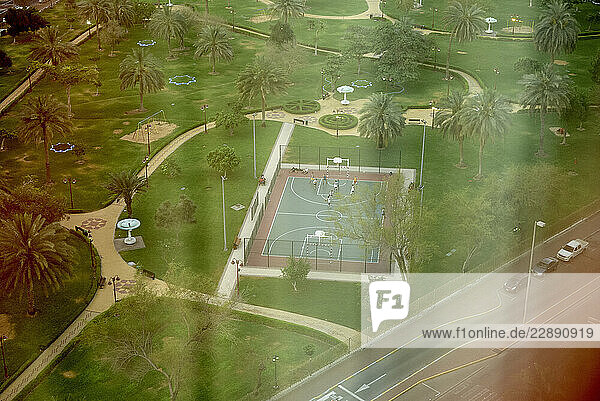 Aerial view of a green park with palm trees and a basketball court. Abu Dhabi  UAE