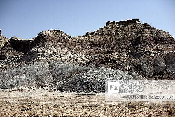 Arid rocky landscape with layered formations under a clear blue sky. USA
