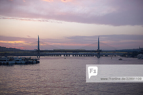 Sunset view of Halic Metro Bridge  or Golden Horn Metro Bridge  over the Golden Horn with boats and a colorful sky. Istanbul  Turkey