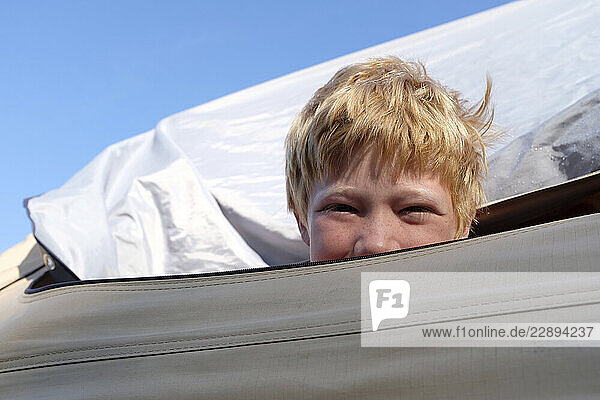 Blonde boy smiling while camping in a tent outdoors