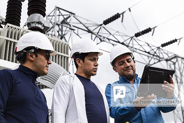 Engineers inspecting an electric transformer at a wind farm