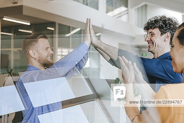 Businesspeople celebrating success with a high five in an office setting