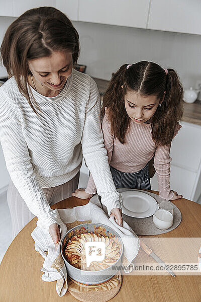 Mother and daughter baking a homemade pie together in the kitchen