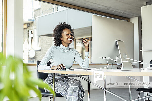 Smiling female professional using computer while sitting at desk in office