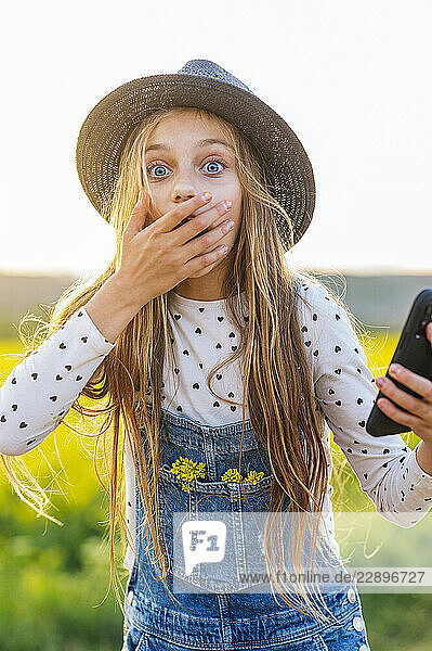Blond girl with shocked expression standing at field