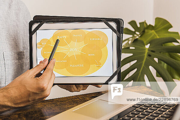 Male healthcare worker pointing on digital tablet during online therapy in office