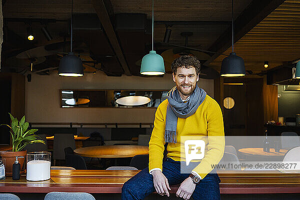 Smiling businessman sitting on table at cafe