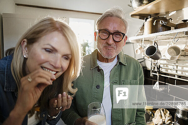 Senior couple enjoying a meal and drink in the kitchen at home