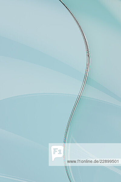Abstract turquoise glass design with curved elements in a 3D render