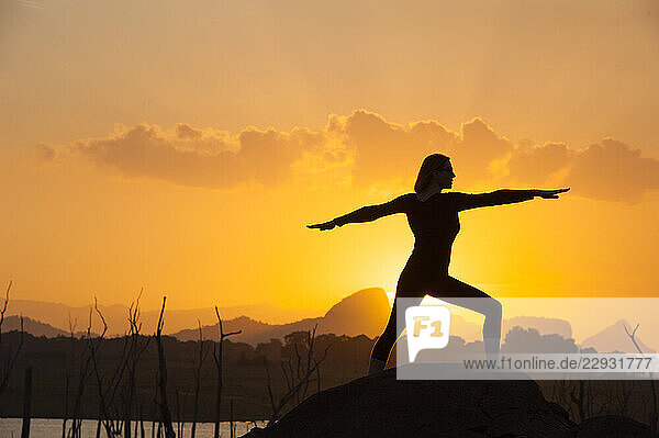 Young woman practising yoga posture by the Senanayake Samudraya Lake at sunset  Gal Oya National Park  Sri Lanka  Indian subcontinent  South Asia