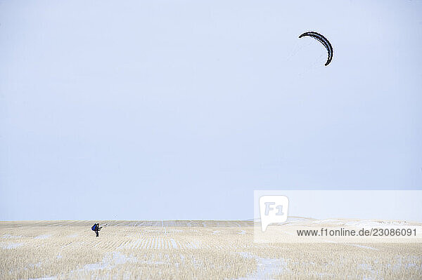 A young man snowkites across a field during the 2XtM expedition