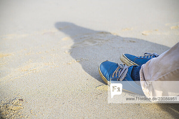 Feet of person sitting on beach