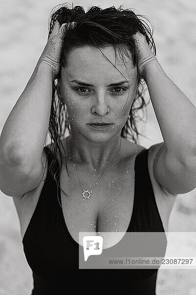Beach portrait of woman with wet hair and sand on face