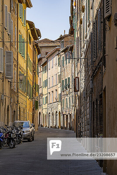 Blick auf eine kleine Straße  die durch alte Gebäude in der Stadt Siena führt  Toskana  Italien  Europa