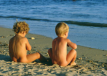 small nudist children Nude children sitting on beach